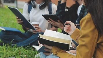 Group of happy young Asian college students sitting on a bench, looking at a laptop screen, discussing and brainstorming on their school project together. video