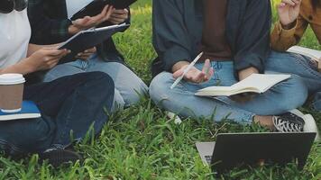 Group of happy young Asian college students sitting on a bench, looking at a laptop screen, discussing and brainstorming on their school project together. video