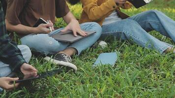 gruppo di contento giovane asiatico Università studenti seduta su un' panca, guardare a un' il computer portatile schermo, discutere e di brainstorming su loro scuola progetto insieme. video