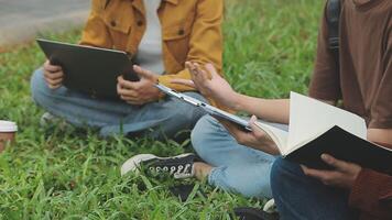 grupo do feliz jovem ásia Faculdade alunos sentado em uma banco, olhando às uma computador portátil tela, discutindo e debate em seus escola projeto junto. video