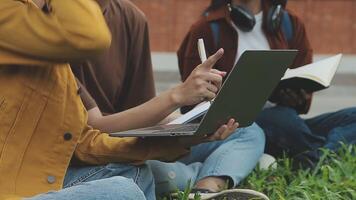 groep van gelukkig jong Aziatisch college studenten zittend Aan een bank, op zoek Bij een laptop scherm, bespreken en brainstorming Aan hun school- project samen. video