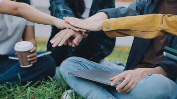 Group of happy young Asian college students sitting on a bench, looking at a laptop screen, discussing and brainstorming on their school project together. video