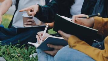 Group of happy young Asian college students sitting on a bench, looking at a laptop screen, discussing and brainstorming on their school project together. video