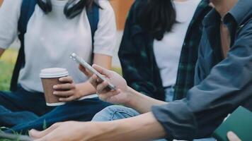 Group of happy young Asian college students sitting on a bench, looking at a laptop screen, discussing and brainstorming on their school project together. video