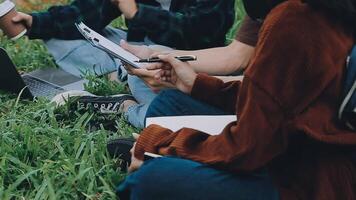 grupo do feliz jovem ásia Faculdade alunos sentado em uma banco, olhando às uma computador portátil tela, discutindo e debate em seus escola projeto junto. video