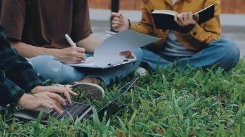 gruppo di contento giovane asiatico Università studenti seduta su un' panca, guardare a un' il computer portatile schermo, discutere e di brainstorming su loro scuola progetto insieme. video