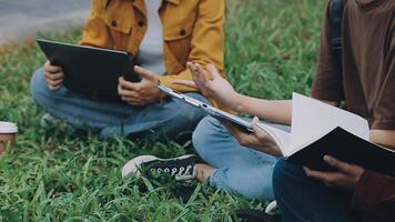 Group of happy young Asian college students sitting on a bench, looking at a laptop screen, discussing and brainstorming on their school project together. video