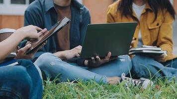 groupe de content Jeune asiatique Université élèves séance sur une banc, à la recherche à une portable filtrer, discuter et réflexion sur leur école projet ensemble. video