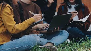 grupo do feliz jovem ásia Faculdade alunos sentado em uma banco, olhando às uma computador portátil tela, discutindo e debate em seus escola projeto junto. video