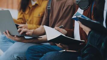 gruppo di contento giovane asiatico Università studenti seduta su un' panca, guardare a un' il computer portatile schermo, discutere e di brainstorming su loro scuola progetto insieme. video