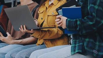 grupp av Lycklig ung asiatisk högskola studenter Sammanträde på en bänk, ser på en bärbar dator skärm, diskuterar och brainstorming på deras skola projekt tillsammans. video