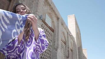 A young woman with long hair in a short white dress and an oriental robe against the background of a wooden gate video