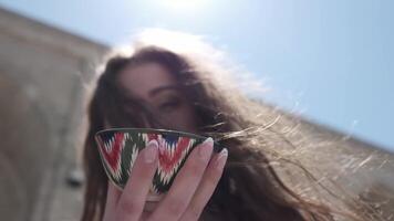 un' giovane donna con lungo capelli Tenere un' dipinto ceramica tè tazza con un uzbeko ornamento nel sua mani video