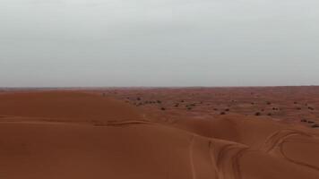 en Drönare flygande över de sand sanddyner av de öken- i dubai på en molnig dag video