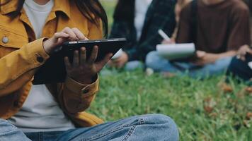 grupo do feliz jovem ásia Faculdade alunos sentado em uma banco, olhando às uma computador portátil tela, discutindo e debate em seus escola projeto junto. video