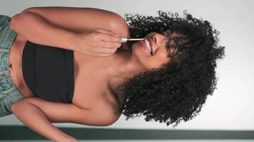 verticaal portret van een jong model- met somber afro haar- en helder verzinnen. verven kubussen met lippenstift. video