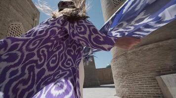 A young woman with long hair in an oriental robe and a skullcap walks through an ancient oriental city video