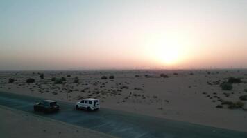 Dubái, uae - 1 14 2023. un zumbido moscas por dos costoso carros conducción en un vacío la carretera entre el playa de el Desierto video