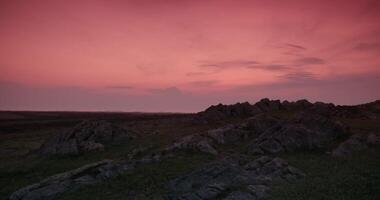 visie van rotsachtig heuvels met struiken en gras tegen een bewolkt zonsondergang lucht video