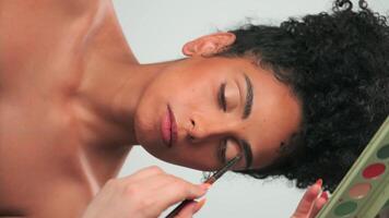 Professional make-up master applies paint to a young model with curly hair video