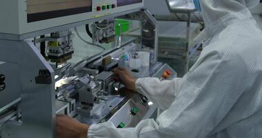 An operator in a protective gown works on an assembly line for the production of electronic devices. video