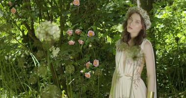 Woman with wreath of flowers walks in the garden video