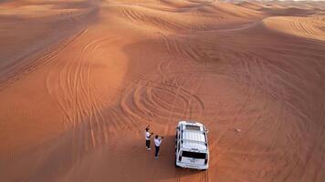 dubai, uae - 1 14 2023. en Drönare flugor över en vit sUV körning genom de sand sanddyner av de öken- video