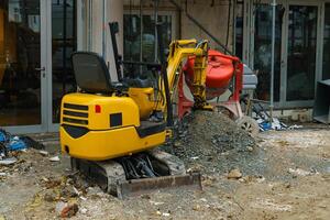 Small yellow excavator and concrete mixer at a construction site. photo