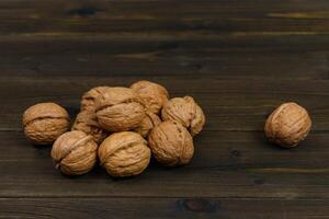 A bunch of walnuts on a dark brown wooden table. photo