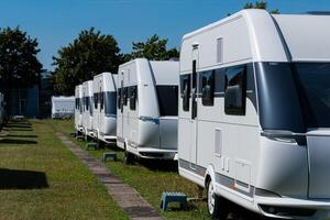 un fila de blanco turismo caravanas en en pie en un soleado día en verano. foto