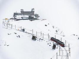 Red Train Ascending Snowy Mountain at Zermatt Ski Resort, Switzerland photo