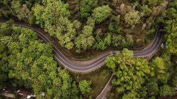 aerial view, asphalt road winding through forest and countryside. photo