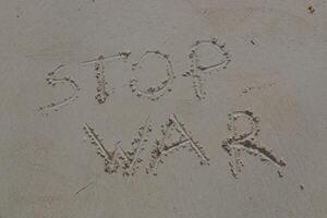 STOP WAR written on white sand photo