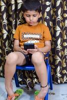 Portrait of Asian smart happy little boy using Mobile phone at home. Little boy holding mobile smart phone, online back to school concept. Online Class concept photo