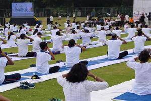 nuevo Delhi, India, junio 21, 2023 - grupo yoga ejercicio sesión para personas a yamuna Deportes complejo en Delhi en internacional yoga día, grande grupo de adultos asistiendo yoga clase en Grillo estadio foto