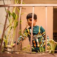 Cute 5 year old Asian little boy is watering the plant in the pots located at house balcony, Love of sweet little boy for the mother nature during watering into plants, Kid Planting photo