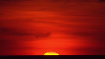 das Sonne ist absteigend unten das Horizont von ein riesig Körper von Wasser, Gießen ein warm, Orange glühen über das still Oberfläche video