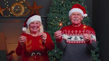 Senior family couple in festive sweaters holding bengal lights enjoying Christmas eve at home room video