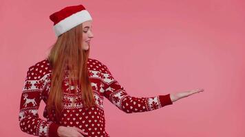 Woman wears red New Year sweater deer showing thumbs up and pointing at on blank advertisement space video