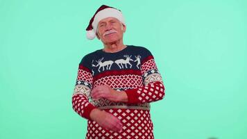 Elderly senior lovely grandfather man wears red New Year sweater and hat smiling, looking at camera video