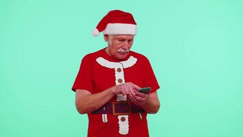 Grandfather in Christmas t-shirt looking smartphone display sincerely rejoicing win success luck video