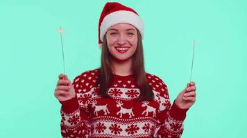 Lovely girl in Christmas Santa sweater dancing with bengal sparklers fireworks ligts, congratulation video