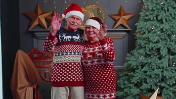 Happy senior Christmas family smiling friendly at camera and waving hands gesturing hello or goodbye video