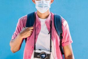 man traveler with vintage camera and holding a backpack wearing a protective mask. photo