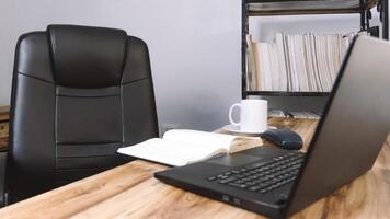 un oficina con un silla un escritorio un ordenador portátil un teléfono un cuaderno y un taza de café. concepto antecedentes. foto