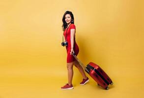 Full length young woman latinx with camera and baggage walking over background. photo