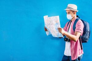 adult man with a backpack wearing a mask holding and looking at a map.f photo