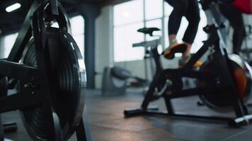 Close-up legs of group unrecognizable friends at gym exercising on stationary bike at class in gym video