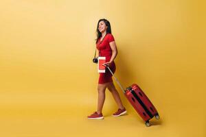 Full length of a latinx woman walking hold a suitcase and passport looking away. photo