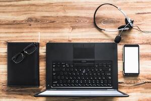 overhead shot of a desk with a laptop an agenda a mobile and headphones with a microphone. call center concept. photo